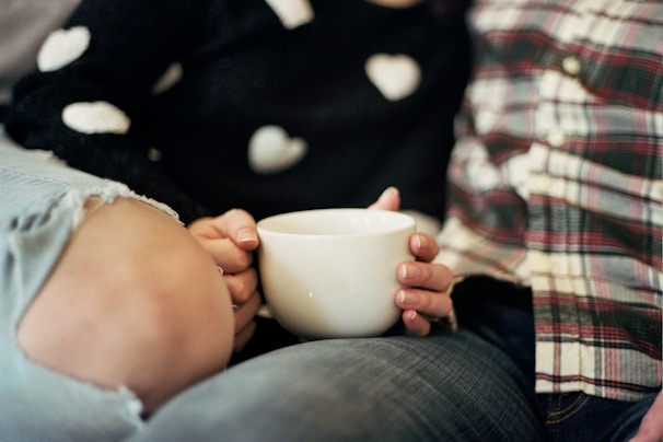 A cozy couple holding matching elegant black and pink mugs, sitting close together.