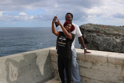 Happy travelers taking selfies with the Caribbean sea in the background.