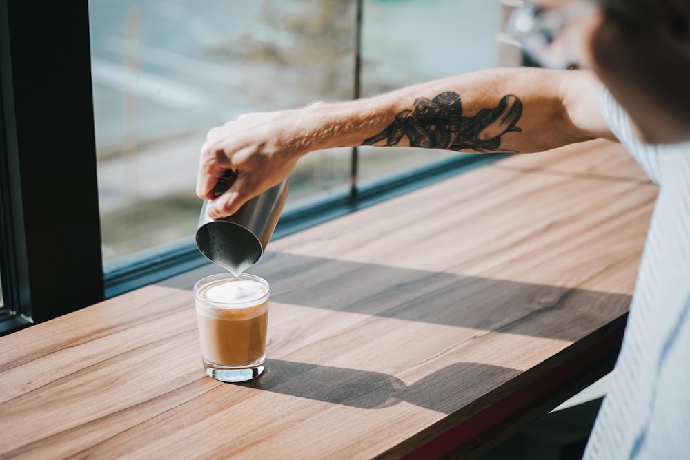 person holding gray stainless steel pitcher