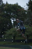 An athlete mid-jump outdoors, wearing Vitalux branded apparel, with a sunset backdrop.