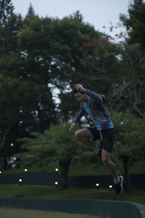 An action shot of a person mid-jump during an outdoor sports activity surrounded by lush greenery.