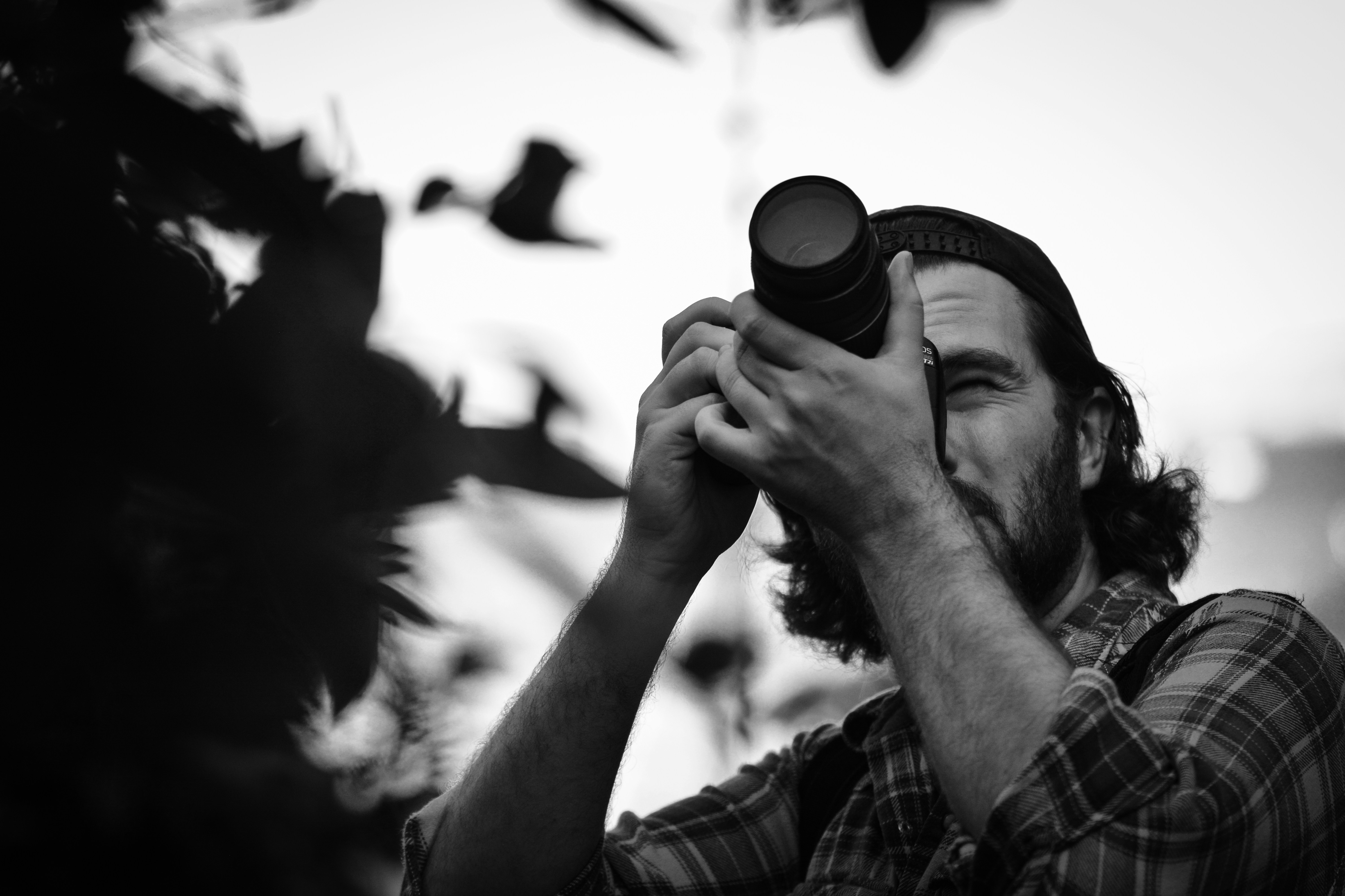 grayscale photography of man taking photo using DSLR camera