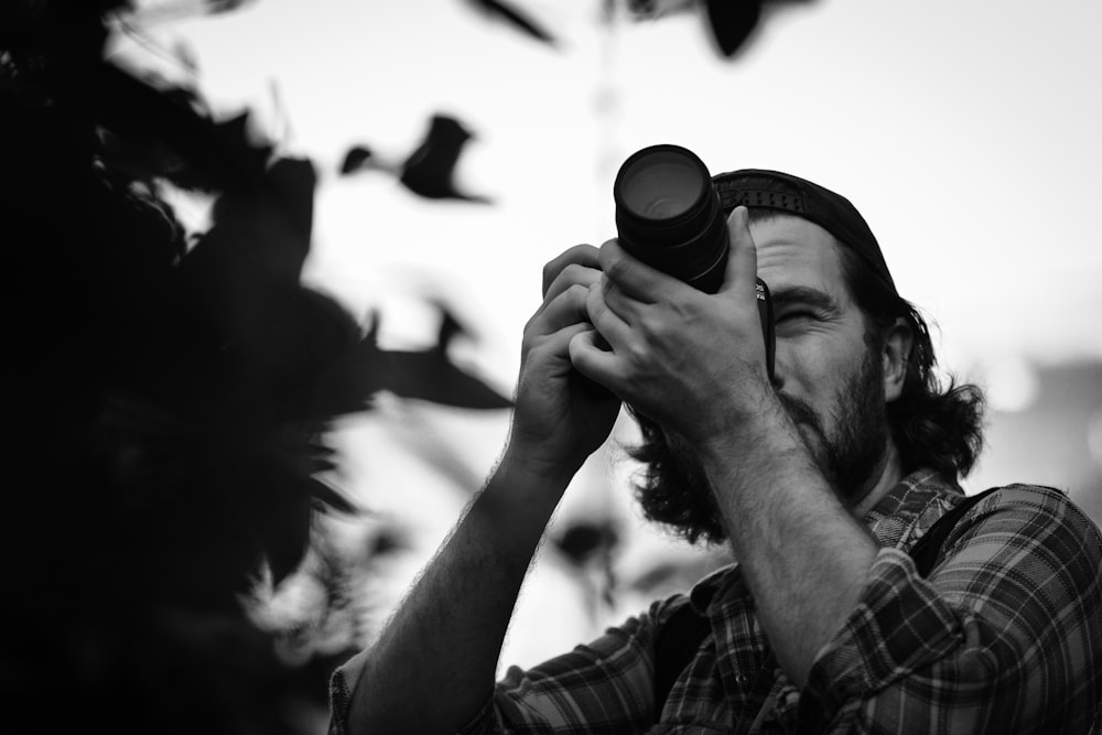 grayscale photography of man taking photo using DSLR camera