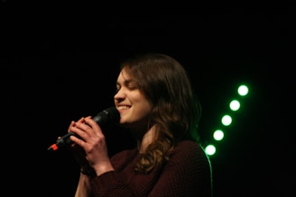 A child singing joyfully into a microphone in a music studio.