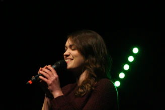 A joyful voice student singing confidently during local band performance.
