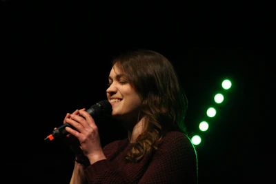 A joyful voice student singing confidently during local band performance.