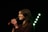 A person singing joyfully into a microphone, surrounded by vibrant lights.
