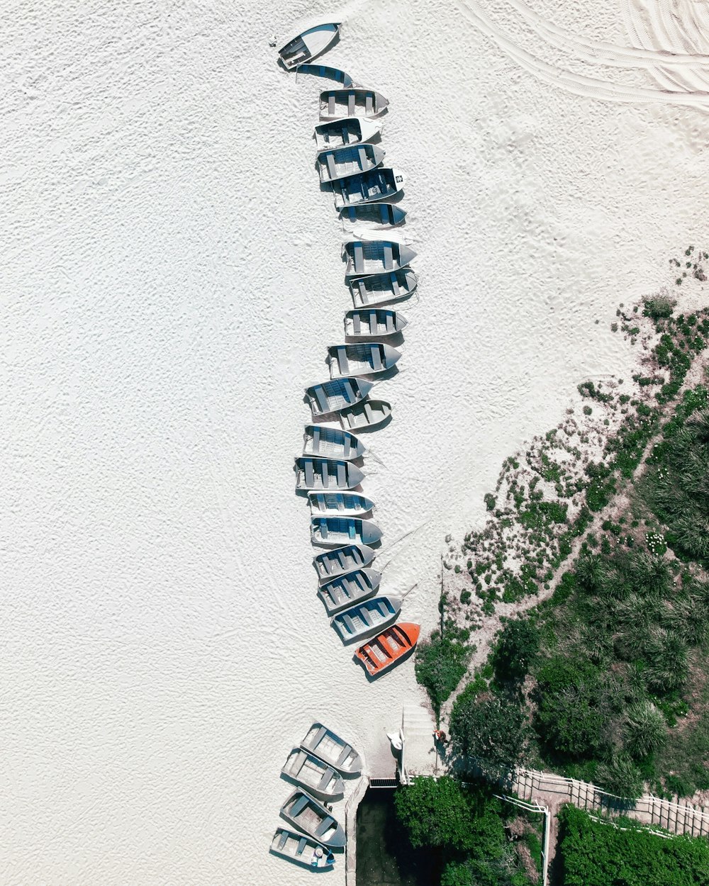 grey and orange canoe boats on white sand near trees at daytime