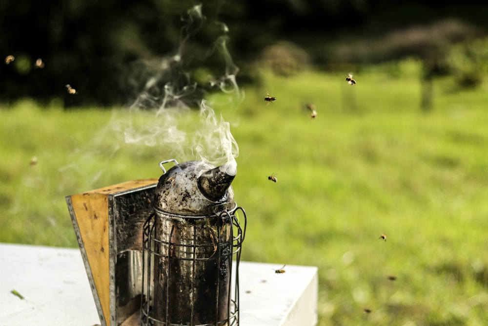 gray metal kettle emitting smoke on white table