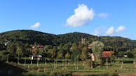A peaceful rural church nestled among green hills under a bright blue sky.