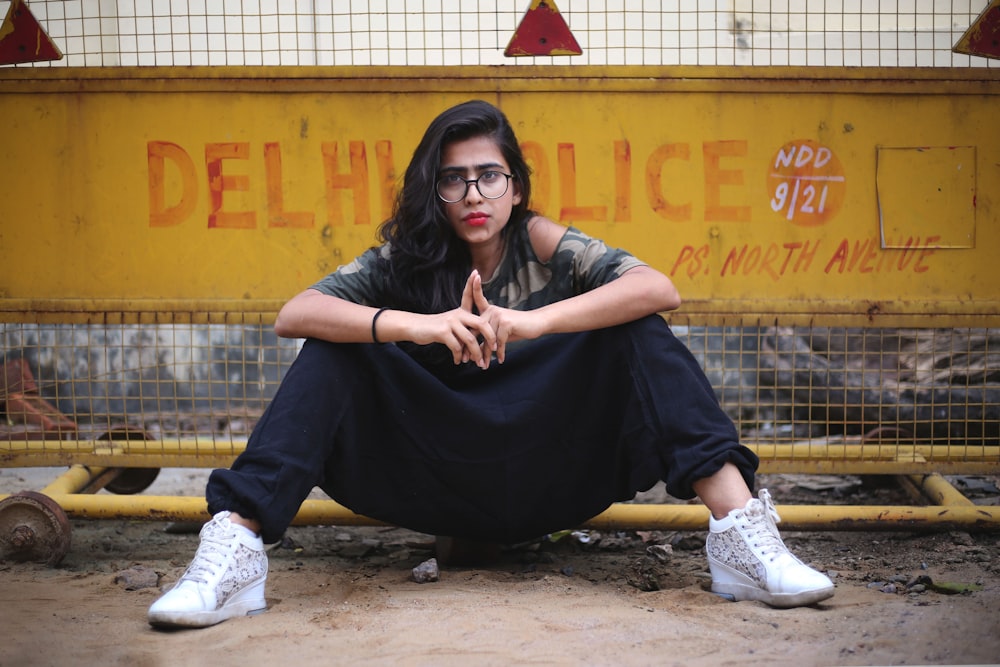 woman sitting on ground near yellow fence