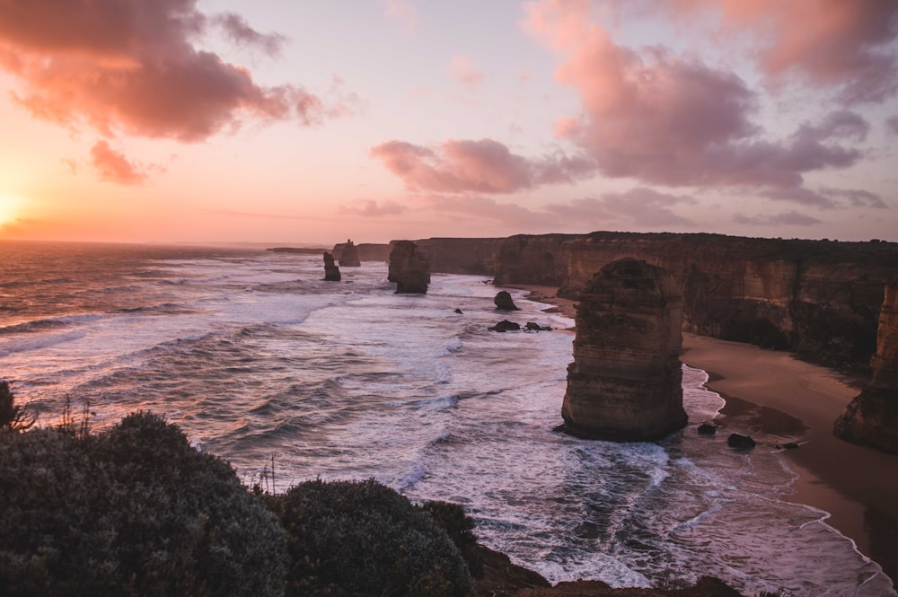 brown rock formations by the shore during sunset