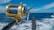 A close-up view of a fishing rod and reel on a boat, angling out over a deep blue ocean with a clear sky and a few clouds. The reel is shiny, metallic, and well-crafted, indicating it is likely for deep-sea fishing.