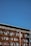 A large outdoor storage area with metal shelves containing multiple car bumpers, arranged in rows and columns. The sky is clear and blue, forming the backdrop of the image.