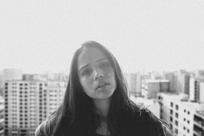 A professional portrait of a young woman with a serene expression against a blurred cityscape.