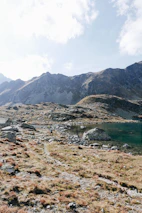 Hikers pausing on a mountain path overlooking a serene lake at sunset.