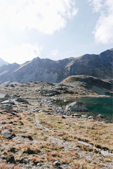 Hikers pausing on a mountain path overlooking a serene lake at sunset.