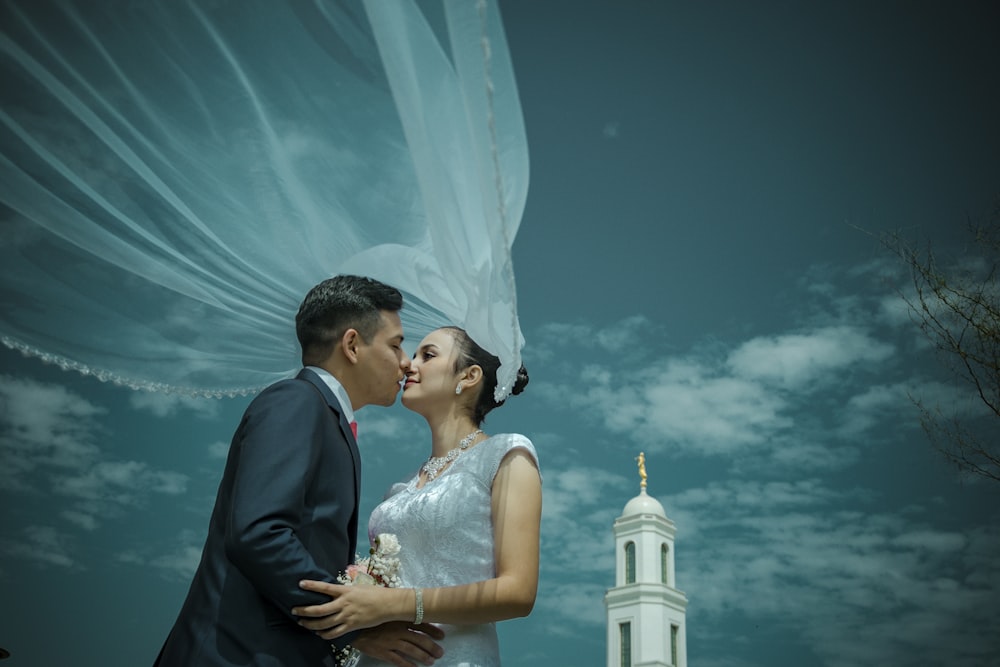 man and woman kissing near white tower