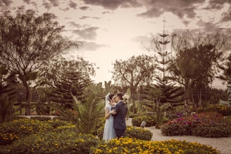 Couple exchanging vows in a serene garden setting framed by blooming flowers and greenery.