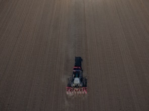 A wide shot of a tractor pulling a plow across a freshly tilled farm.