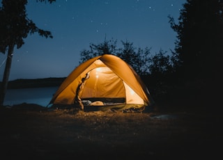 brown dome tent near trees at night