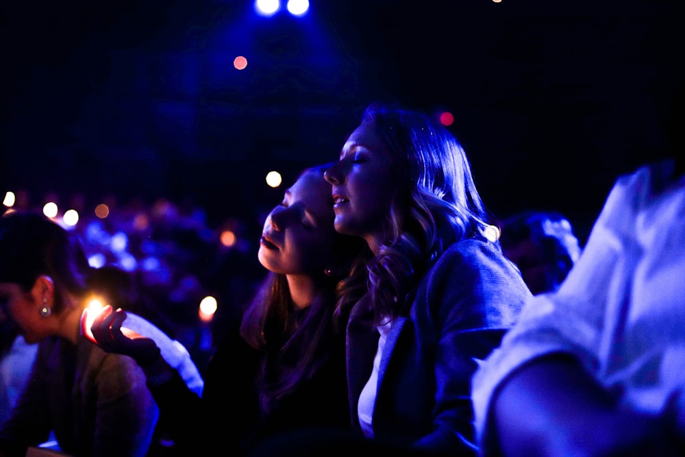 two women sitting beside each other surrounded with sea of people