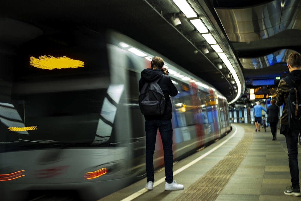 panning photography of man standing beside train
