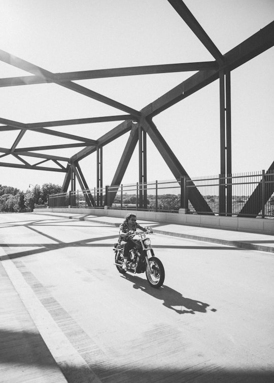 grayscale photo of man riding motorcycle on bridge in Minneapolis United States