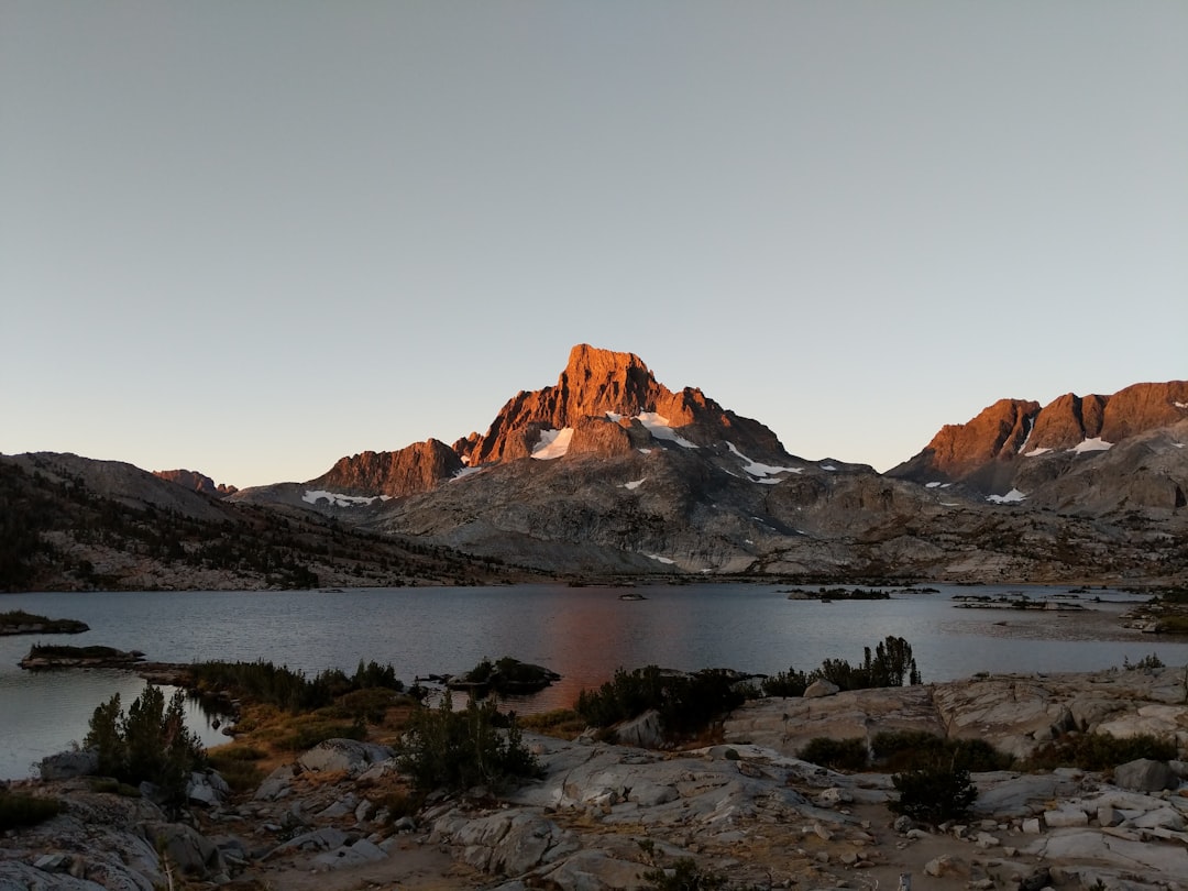 brown mountain near body of water during daytime