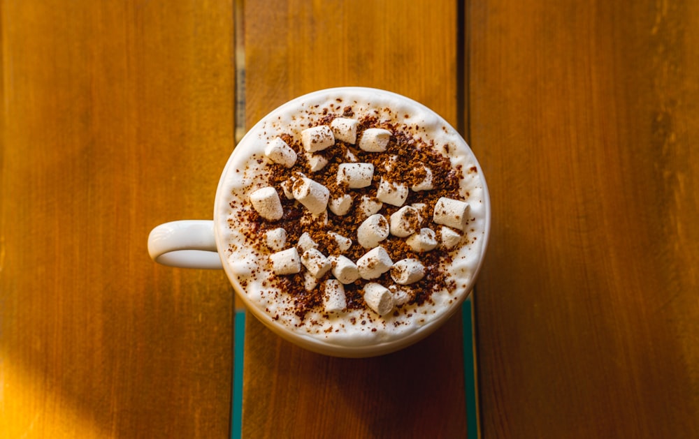 Cappuccino in Teetasse auf brauner Holzoberfläche