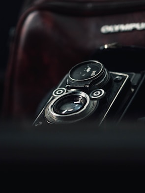 Close-up of a vintage film camera with blurred lights in the background.