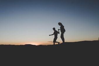 silhouette of man and woman walking on mountain
