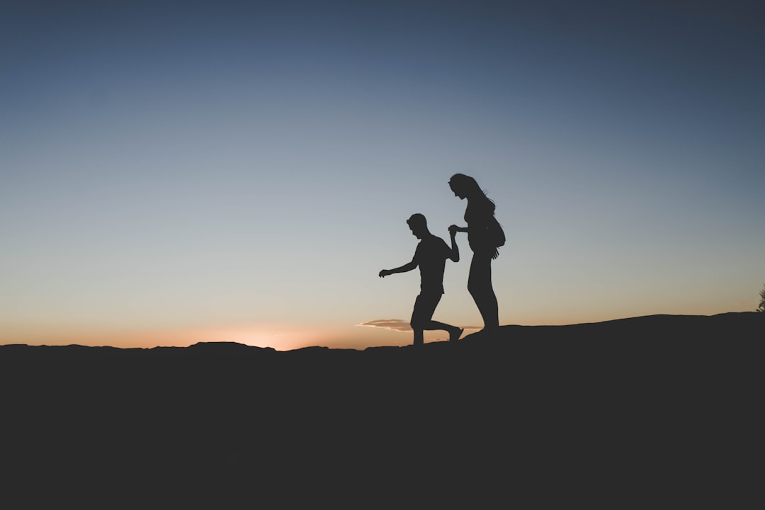 silhouette of man and woman walking on mountain, hold me