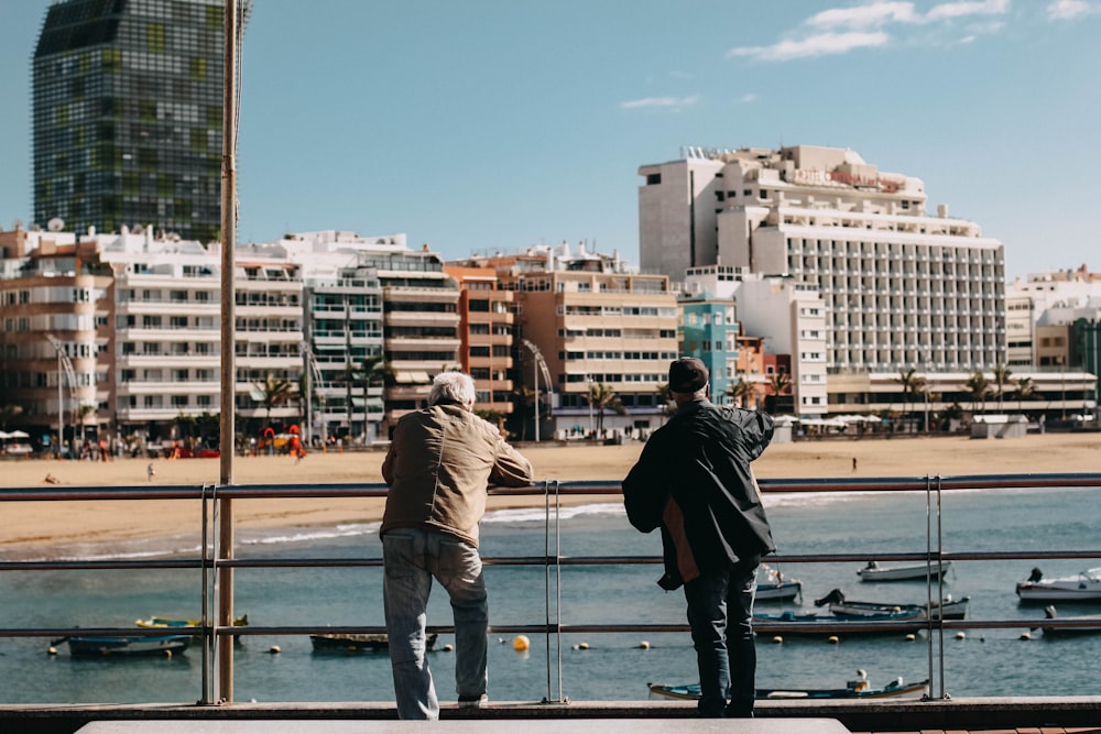 two men leaning on metal rails