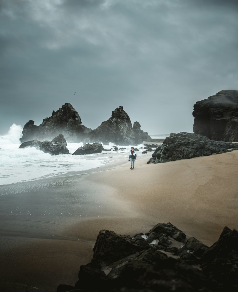 person standing beside rock