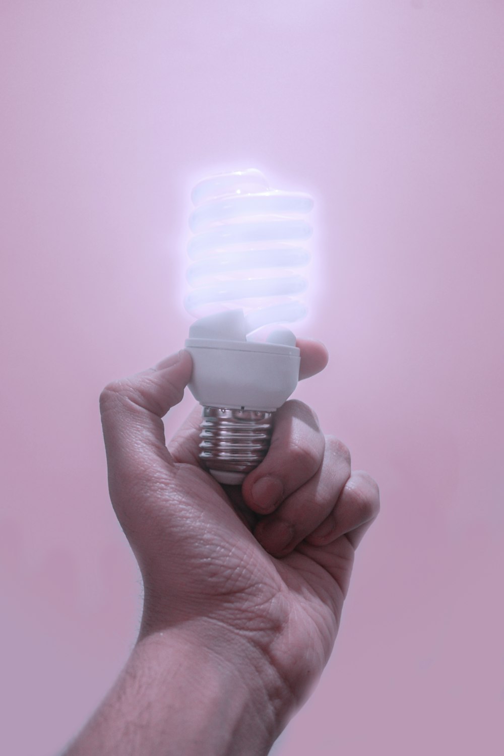 person holding CFL light bulb turned-on