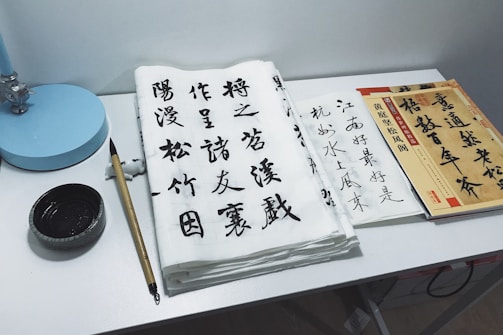 A serene workspace with traditional Japanese tea utensils and a calligraphy brush resting on rice paper.