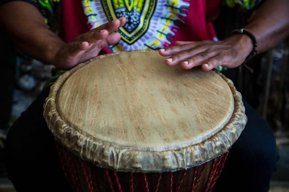 person thumping the round brown and beige drum