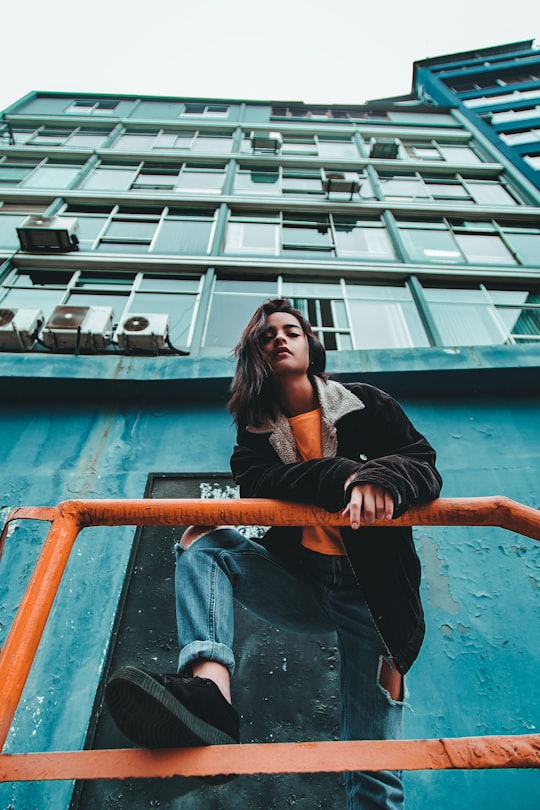 woman standing near orange metal railing on green concrete building in Lima Peru