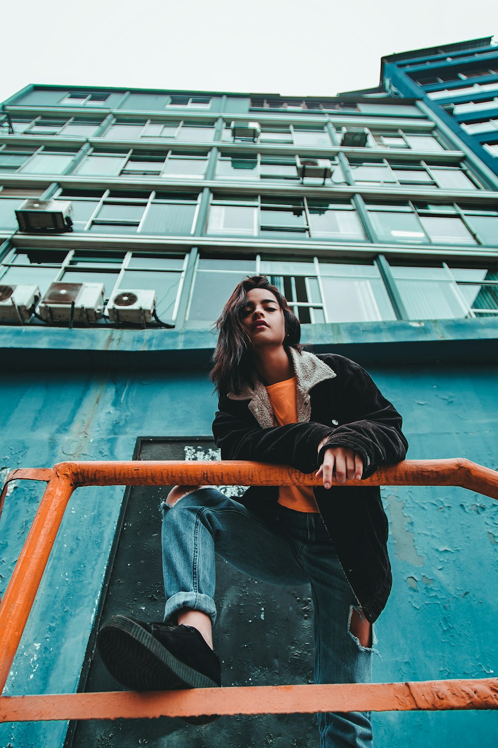 woman standing near orange metal railing on green concrete building