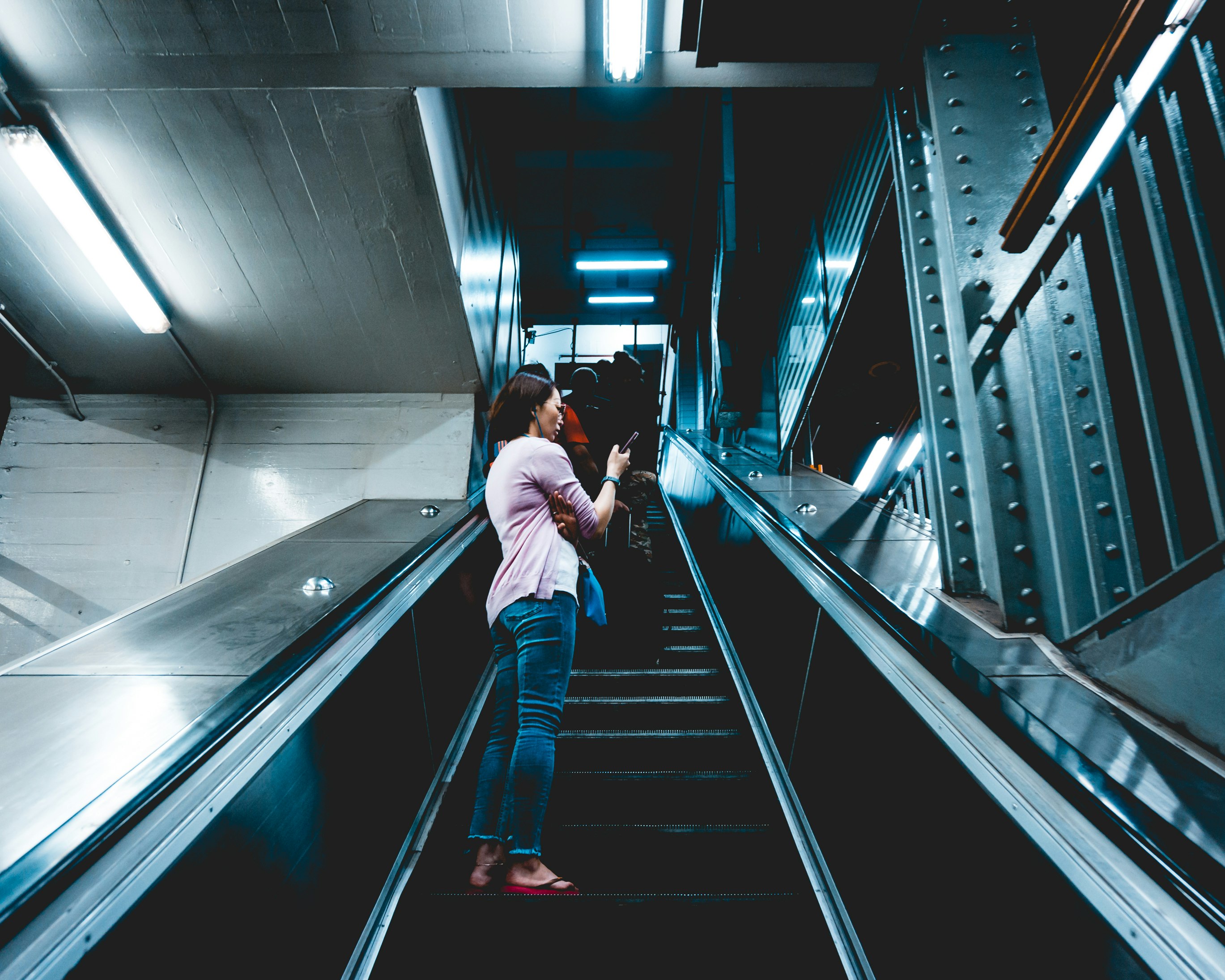 woman standing and using phone on escalator