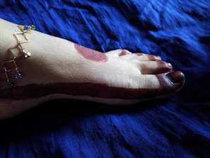 Artistic shot of a bride’s feet decorated with symmetrical mehndi patterns framed by maroon and gold fabric.