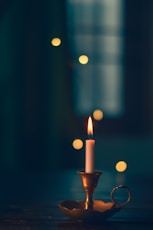 wax candle lit on brass candle holder
