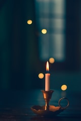 white candle lit on brass candle holder