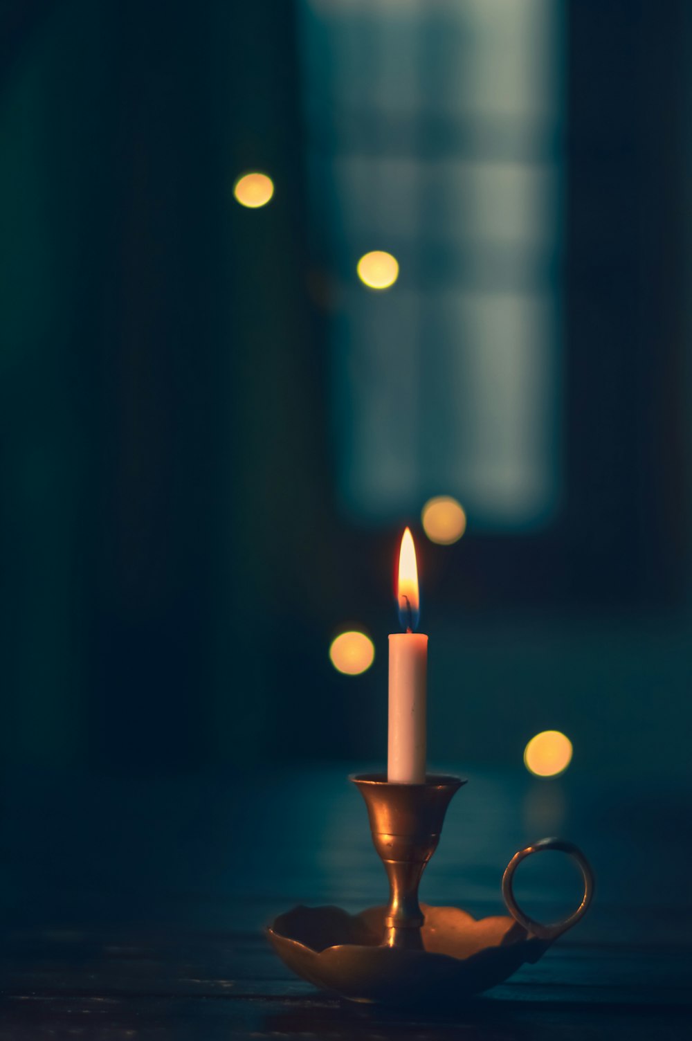 white candle lit on brass candle holder