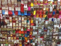 A vibrant display of a wide variety of earrings arranged on a wall, featuring tassels, metallic designs, and colorful beads. The earrings are organized in neat rows, showcasing an array of designs from traditional to modern styles.