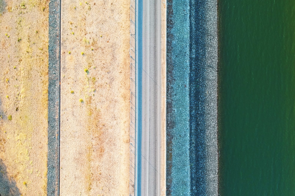 an aerial view of a road next to a body of water