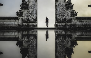 man standing between ruins in reflective photography