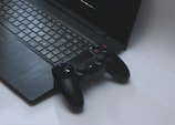 black Sony DualShock 4 controller on black laptop computer