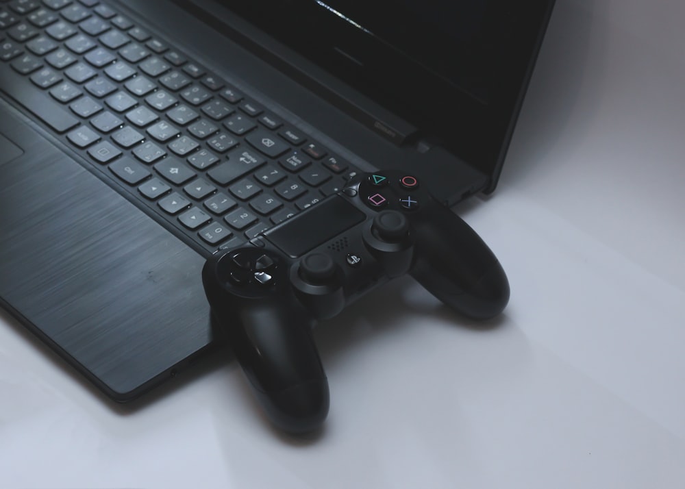 black Sony DualShock 4 controller on black laptop computer
